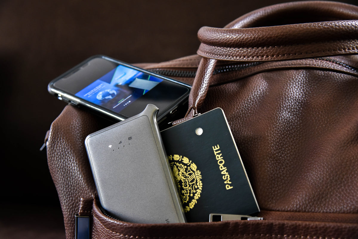 Boîtier Pocket WiFi My Webspot posé sur un passeport et un sac de voyage